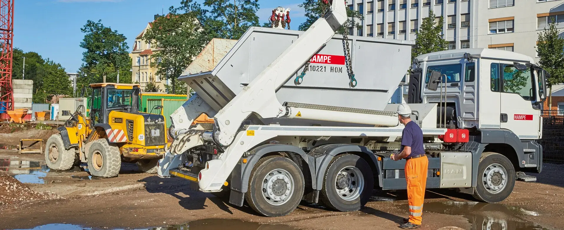 Absetzcontainer auf Baustelle, im Hintergrund ein Bagger