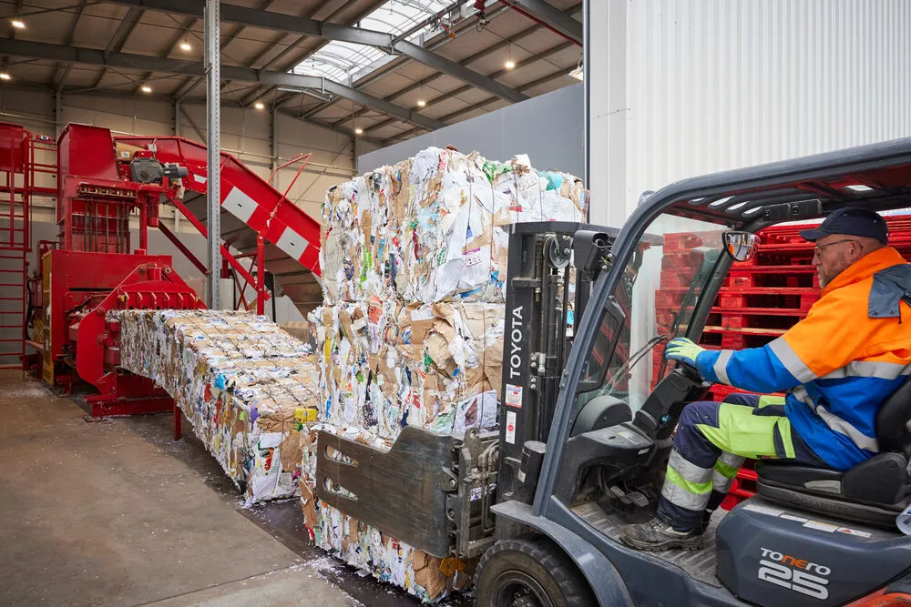 gepresste Papierballen werden von einem Radlader zur Sortieranlage transportiert