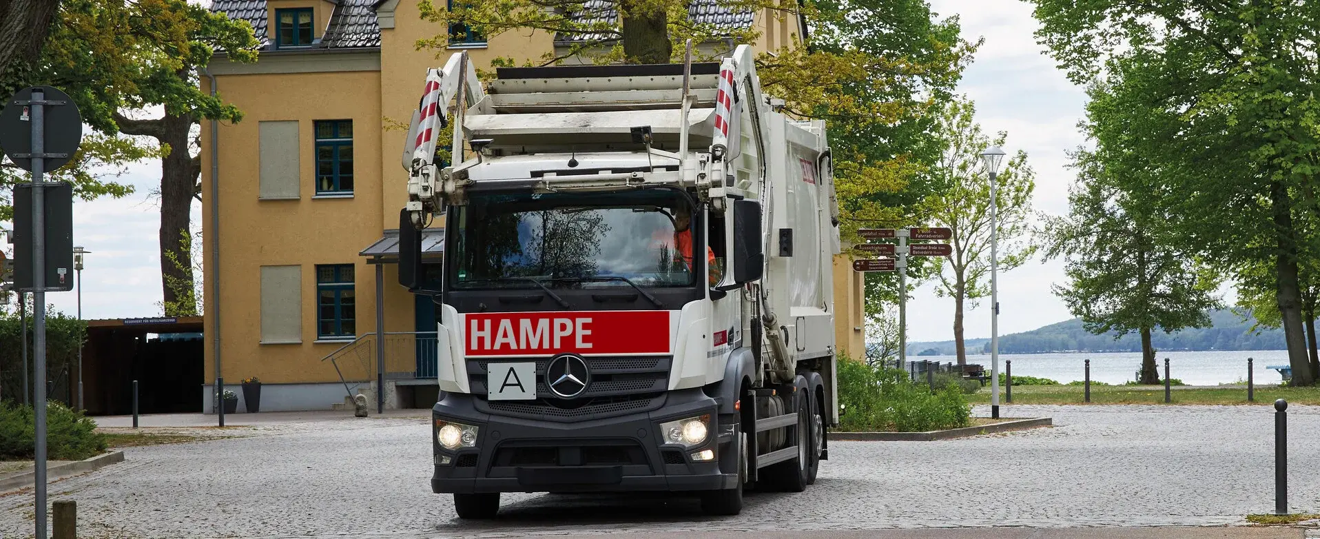 Überkopflader in einer Straße; im Hintergrund ein Wohnhaus und Bäume