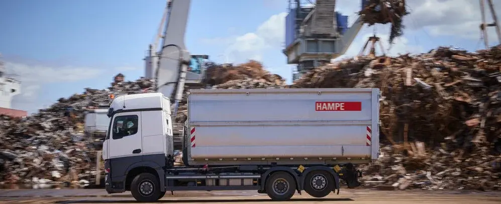 Absetzcontainerfahrzeug welches mit Abfällen beladen wird.